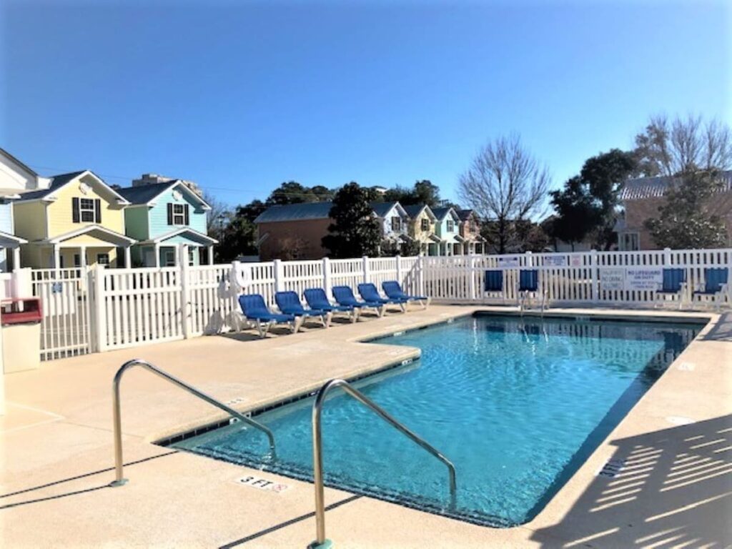 A pool with blue chairs and white fence