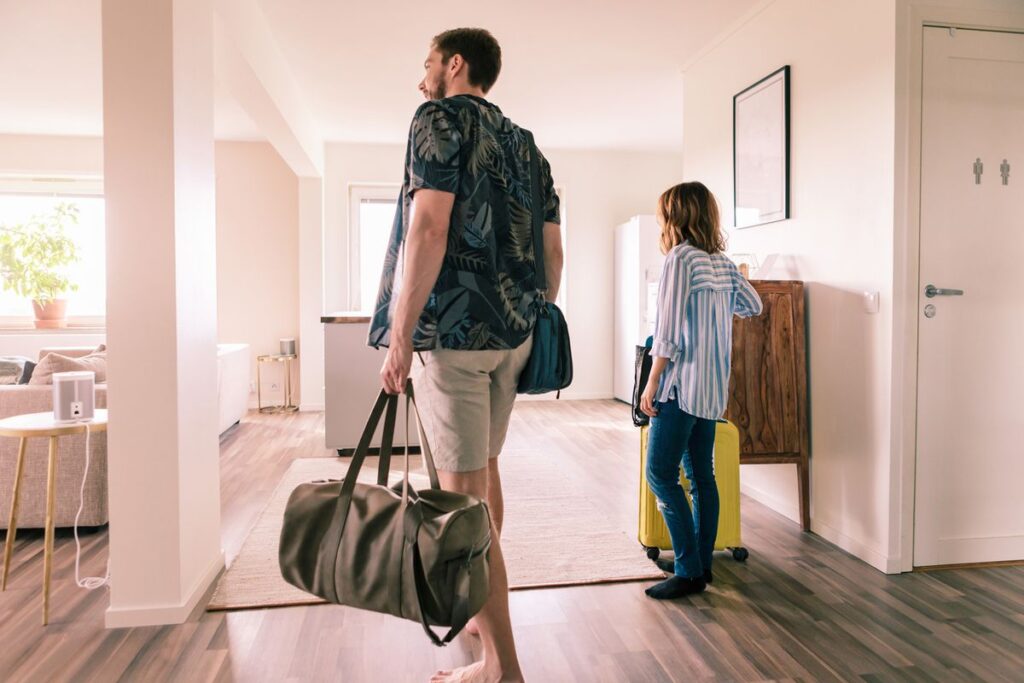 A man and woman walking in the hallway with luggage.