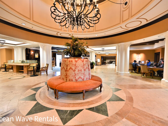 A lobby with a round bench and chandelier.