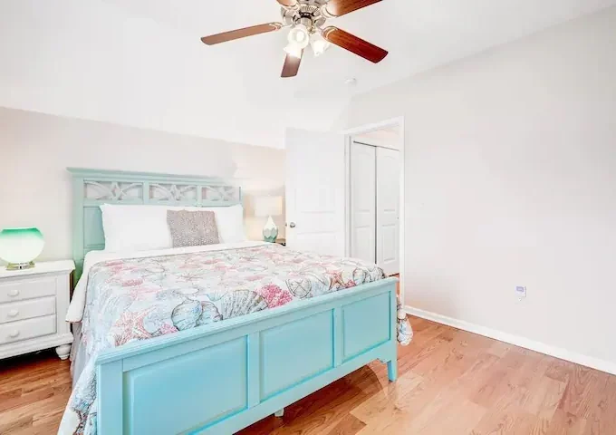 A bedroom with a bed, dresser and ceiling fan.