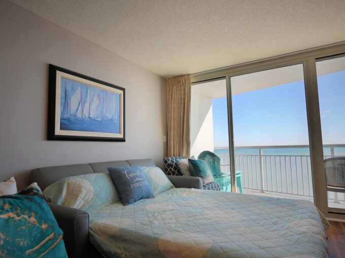 A bedroom with a view of the ocean and a bed.