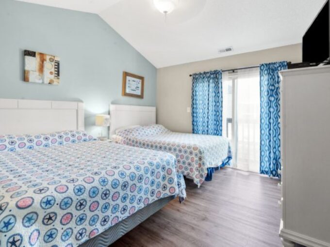 A bedroom with two beds and blue curtains