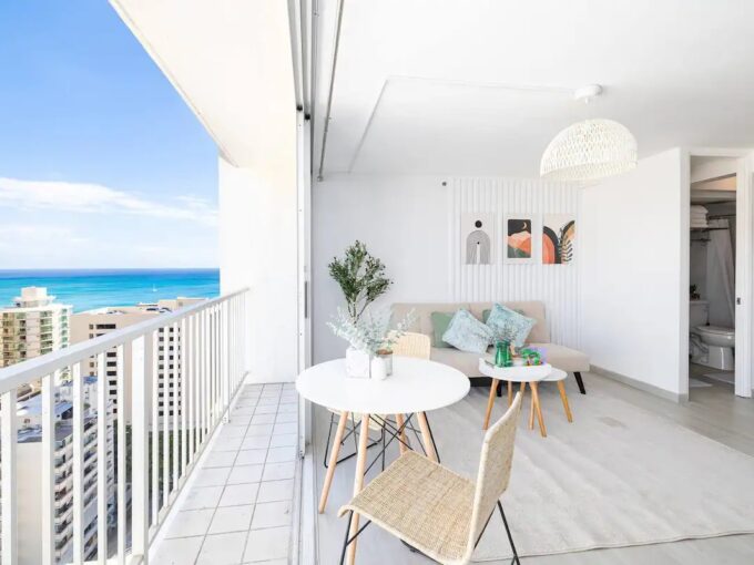 A balcony with chairs and tables overlooking the ocean.