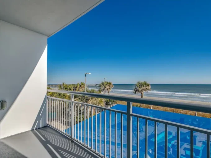 A balcony with a view of the ocean and palm trees.