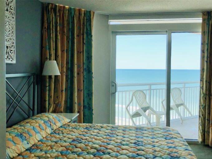 A bedroom with a view of the ocean and beach.