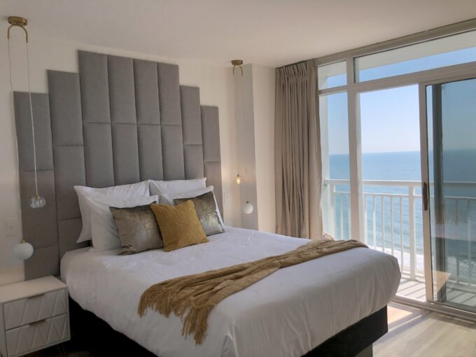 A bedroom with a bed and a balcony overlooking the ocean.