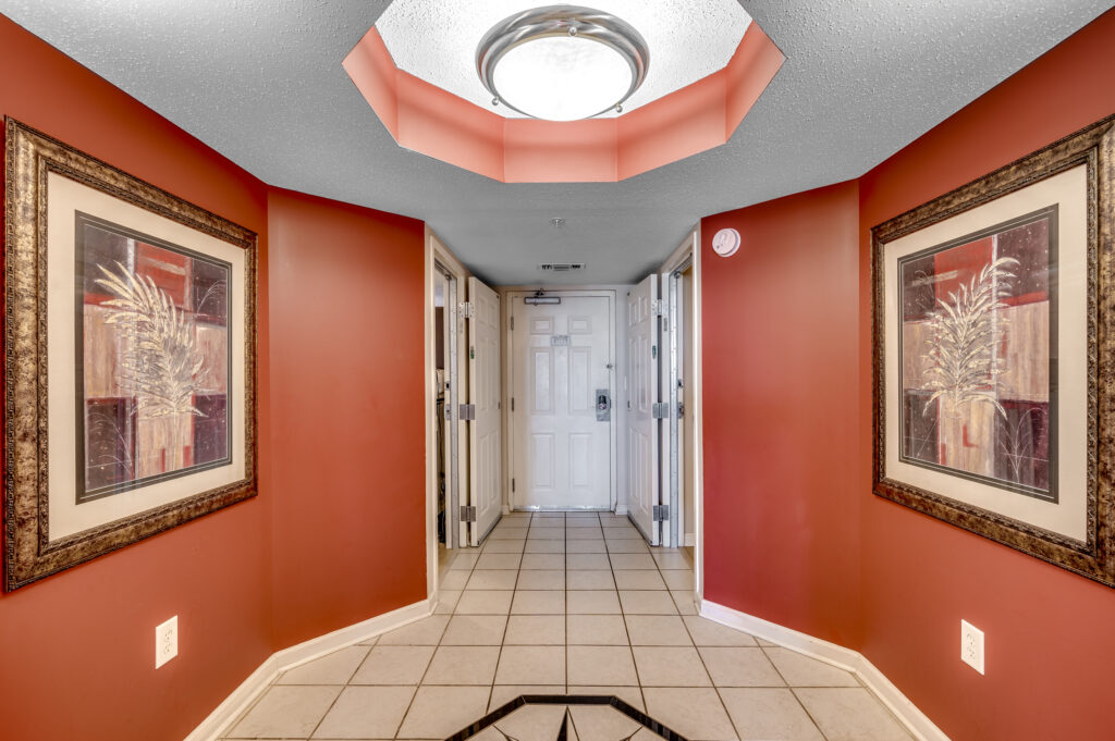 A hallway with red walls and white tile floors.