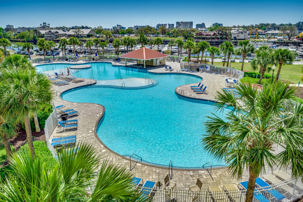 A pool with many chairs and umbrellas in it