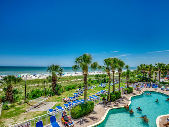 A view of the beach from above, with people swimming in the pool.