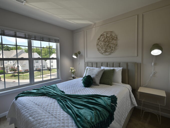 A bedroom with a bed, nightstand and window.