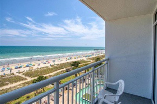 A balcony with chairs and a view of the beach.